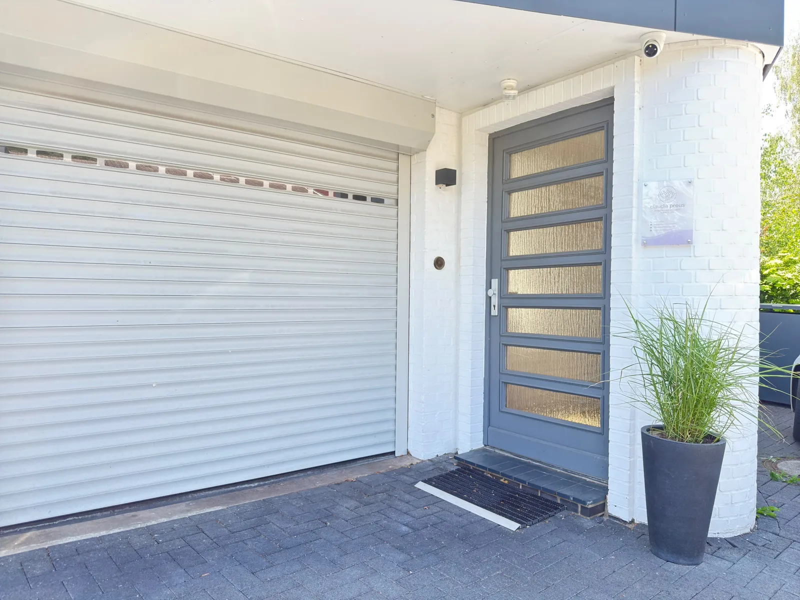 Praxiseingang der Massage- und Wellnesstherapie von Claudia Preus mit grauer Tür und Praxisschild am Birkenweg 11 in Wedel