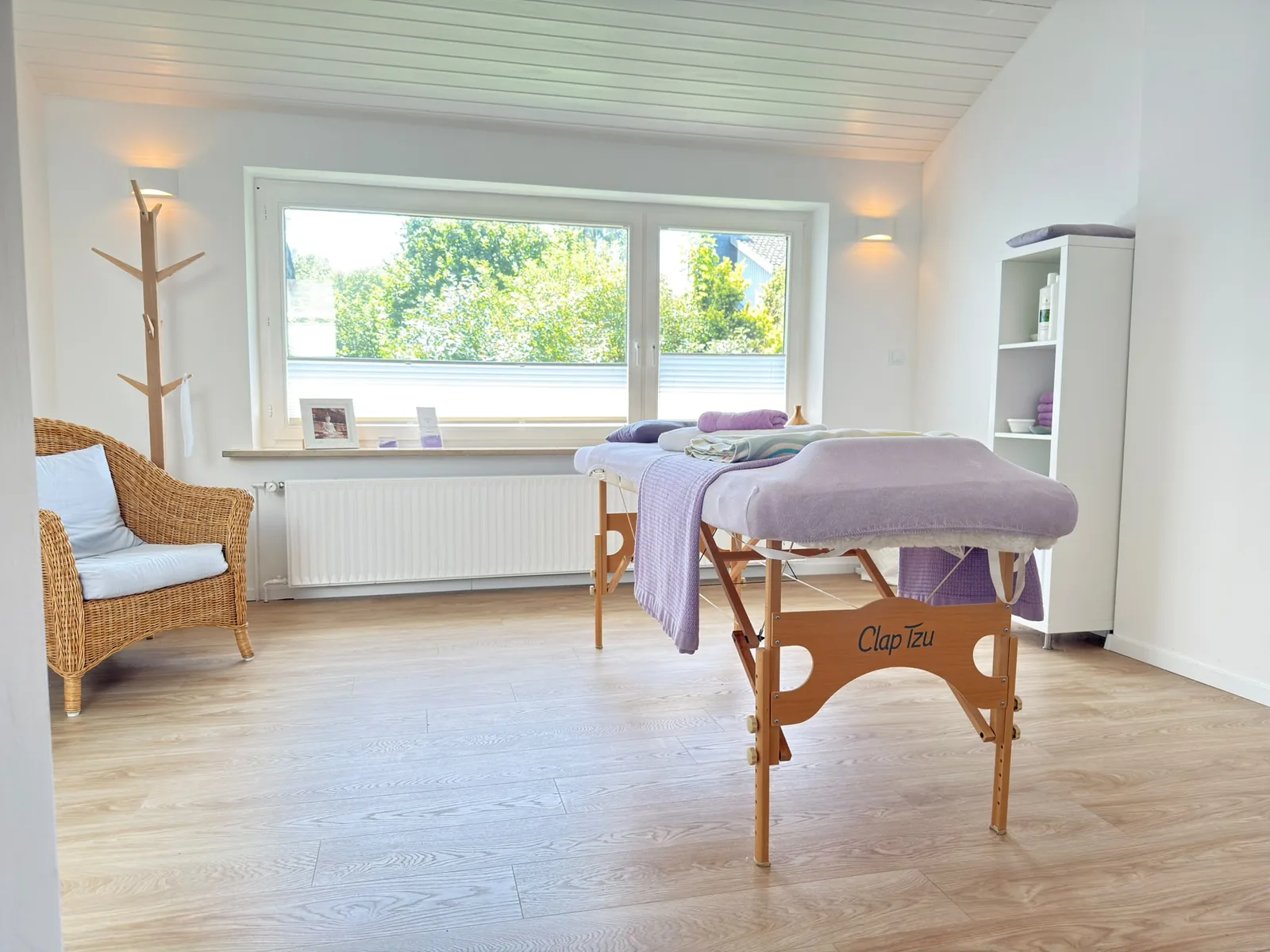 Heller Behandlungsraum der Massage- und Wellnesstherapie von Claudia Preus mit Massageliege und Blick ins Grüne